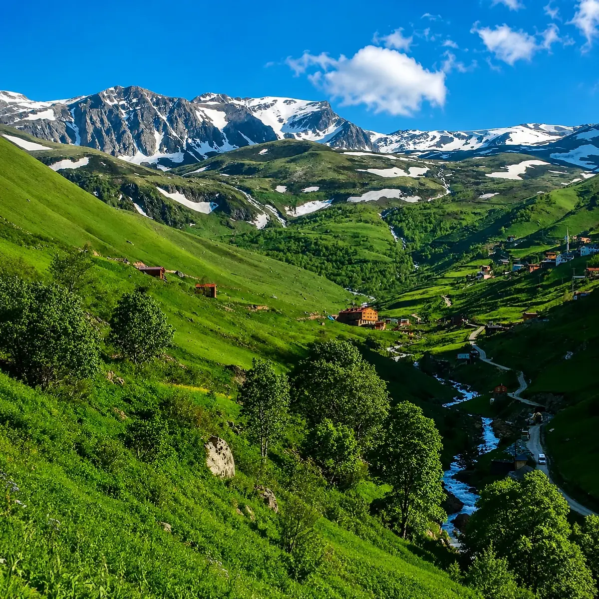 نقاط الإطلالة العليا في ديمير كابي على وادٍ أخضر وقرى جبلية وجدول ماء وسط القمم المكسوّة بالثلج قرب أوزنجول